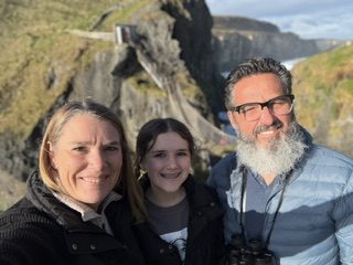 The Eaton family smiling together on the rugged sea cliffs near Carrick-a-Rede, Northern Ireland