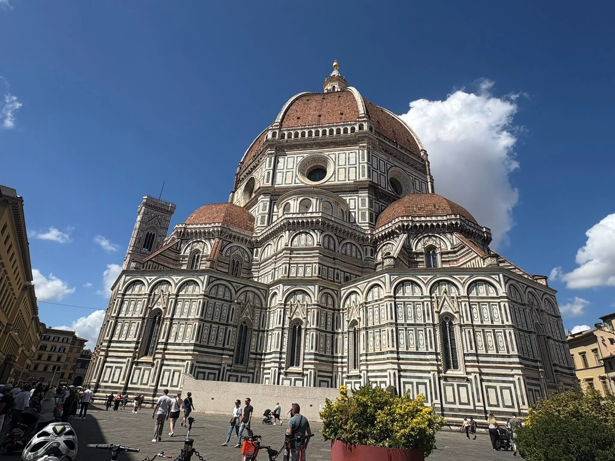 Tourists and bicycles in the Piazza del Duomo beneath Brunelleschi's terracotta dome in Florence, Italy